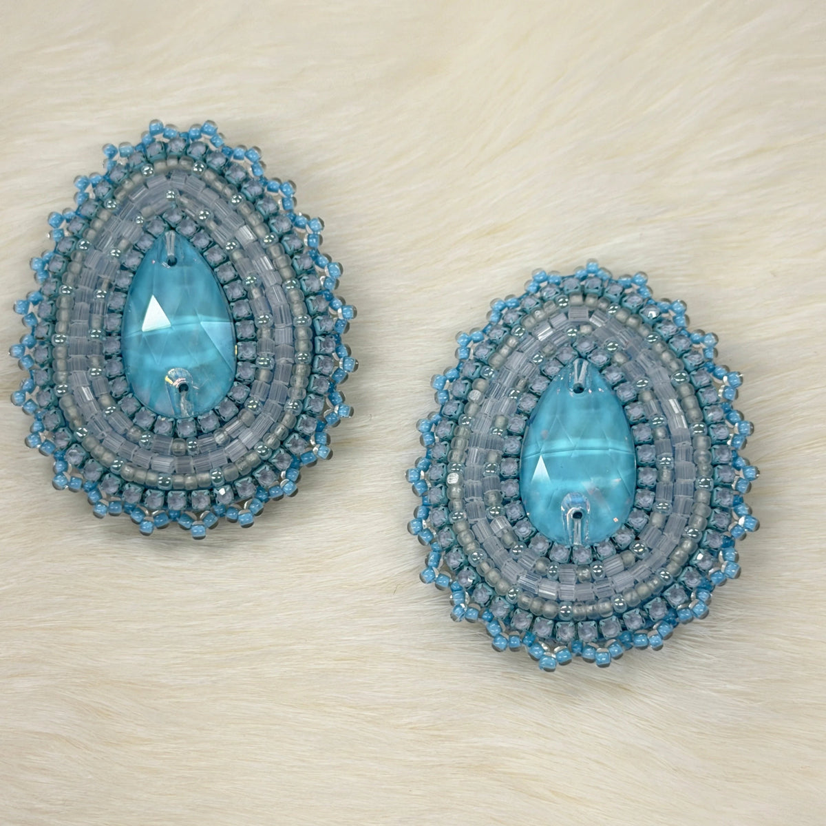 Pair of blue and gray beaded earrings on a light wood surface
