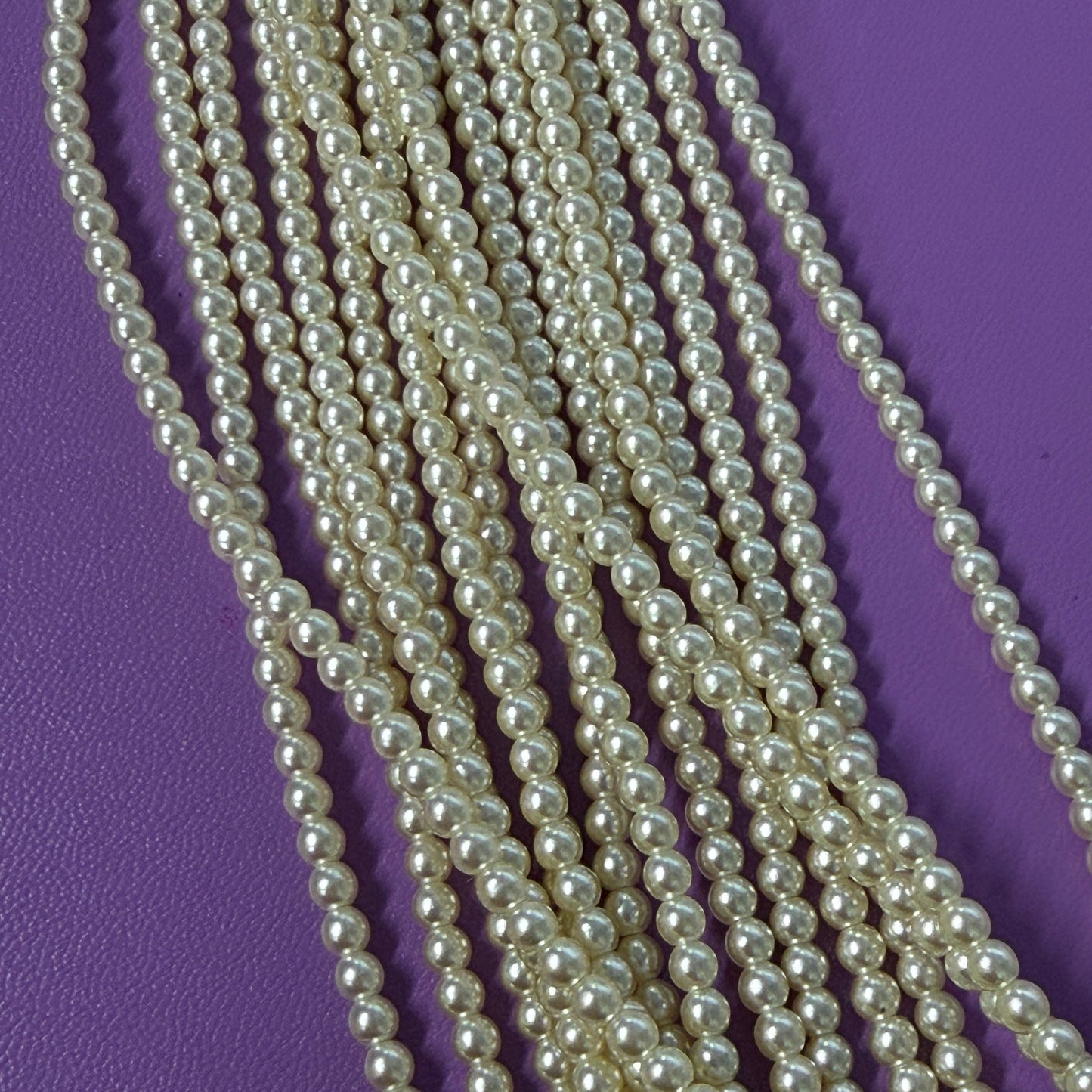 Multiple strands of pearl beads on a purple background