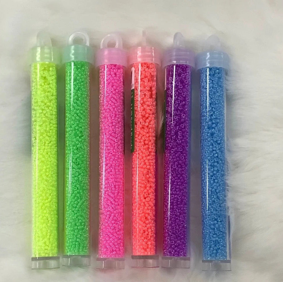 Five tubes of colorful beads on a white surface