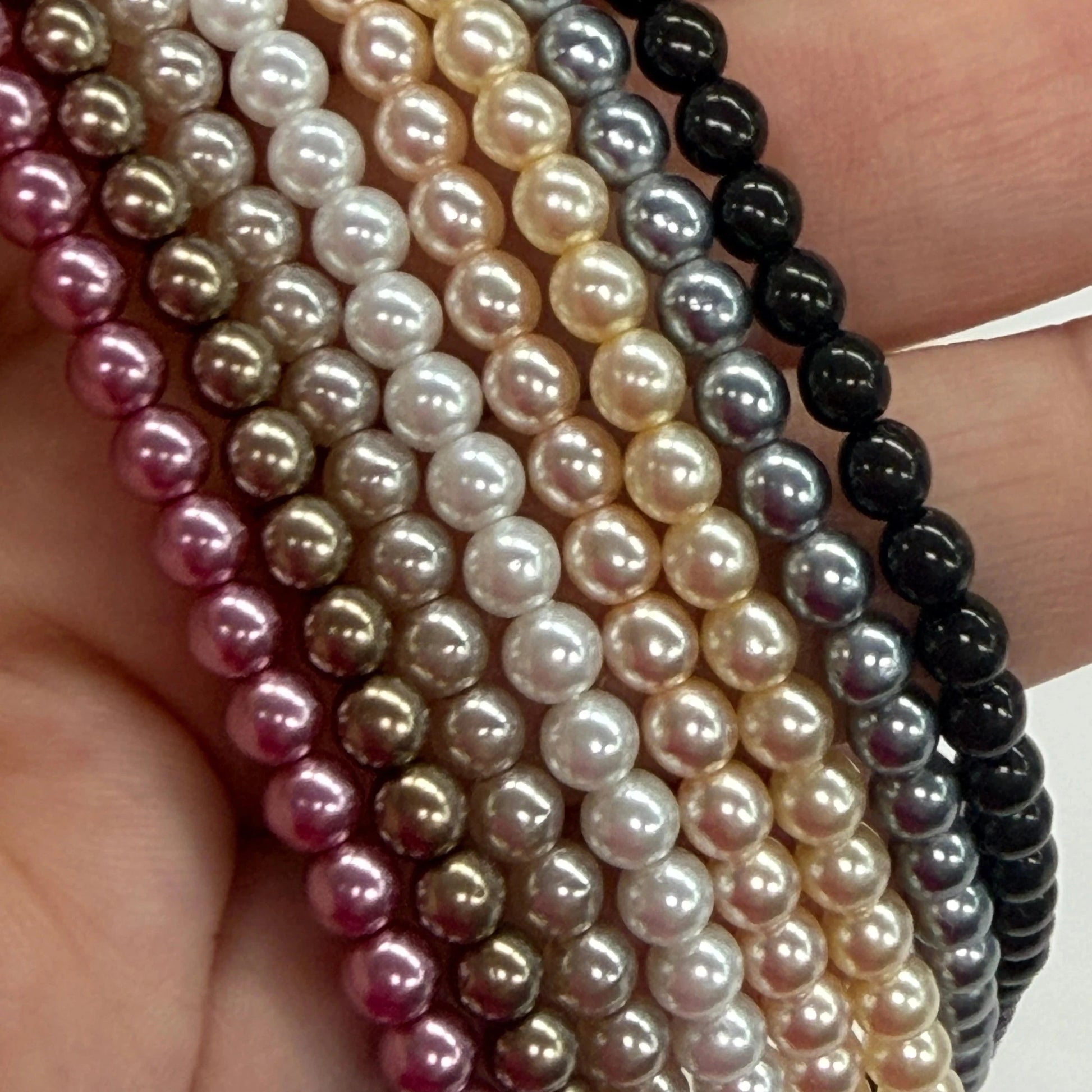 Close-up of multiple strands of pearls held in a hand.