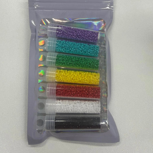 Set of colorful beads in transparent tubes inside a clear plastic bag on a light gray background