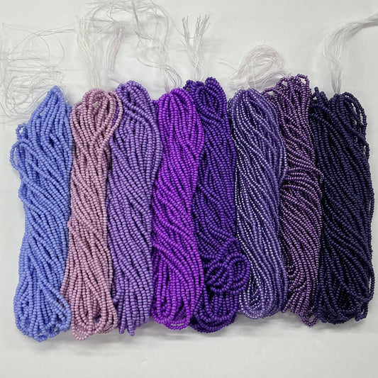 Set of purple and pink yarn skeins on a white background
