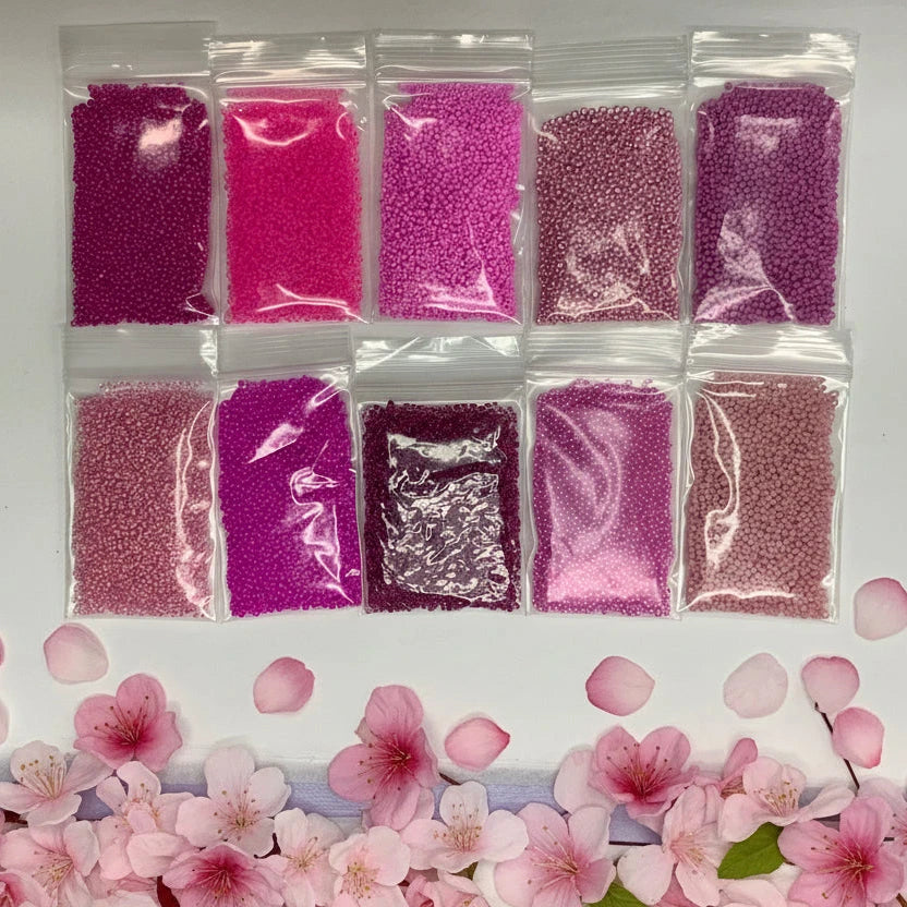 Nine small plastic bags with pink and red contents on a white surface.