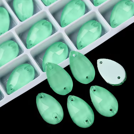 Green teardrop-shaped beads in a white tray on a black background