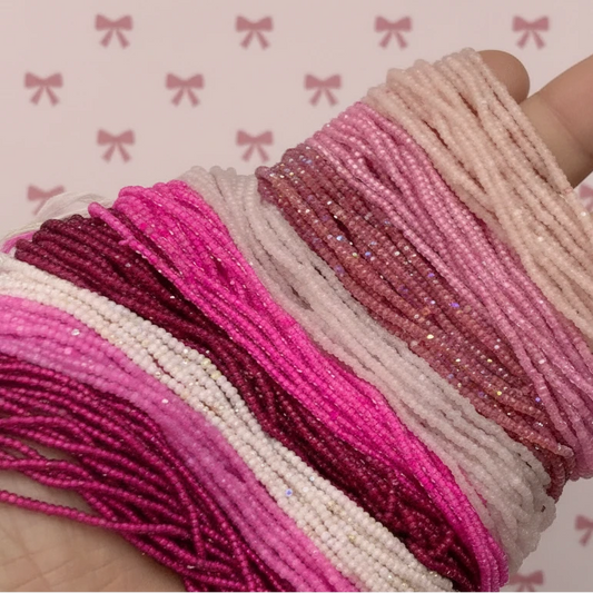 Multiple beaded bracelets in pink and beige colors on a white surface.
